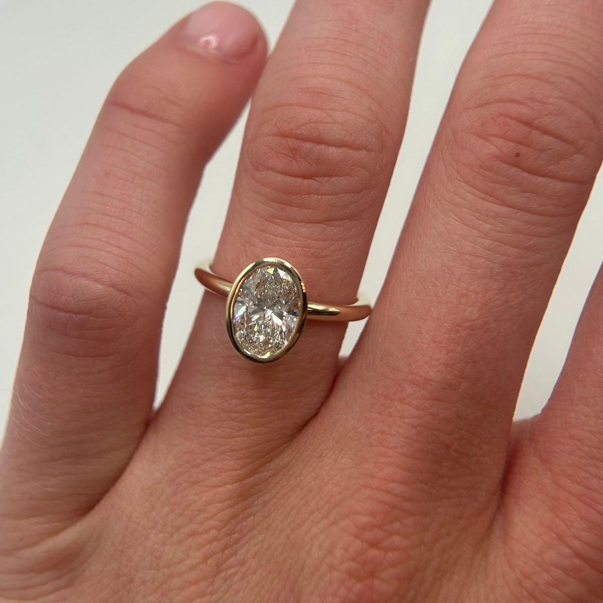 Ovaler Bezel-Verlobungsring mit Labordiamant an der Hand