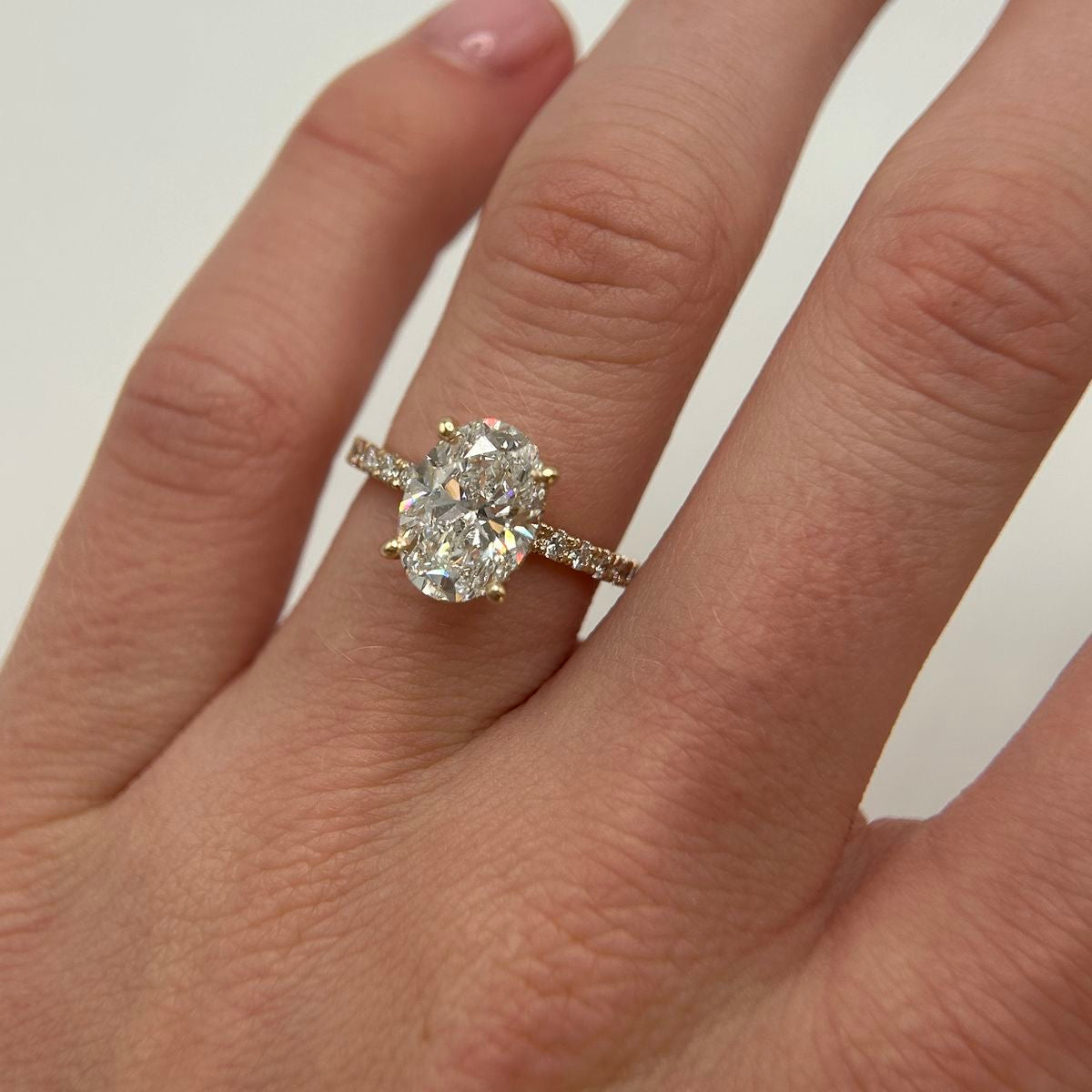 Ovaler Verlobungsring mit Diamant und Pavé-Ringschiene an der Hand