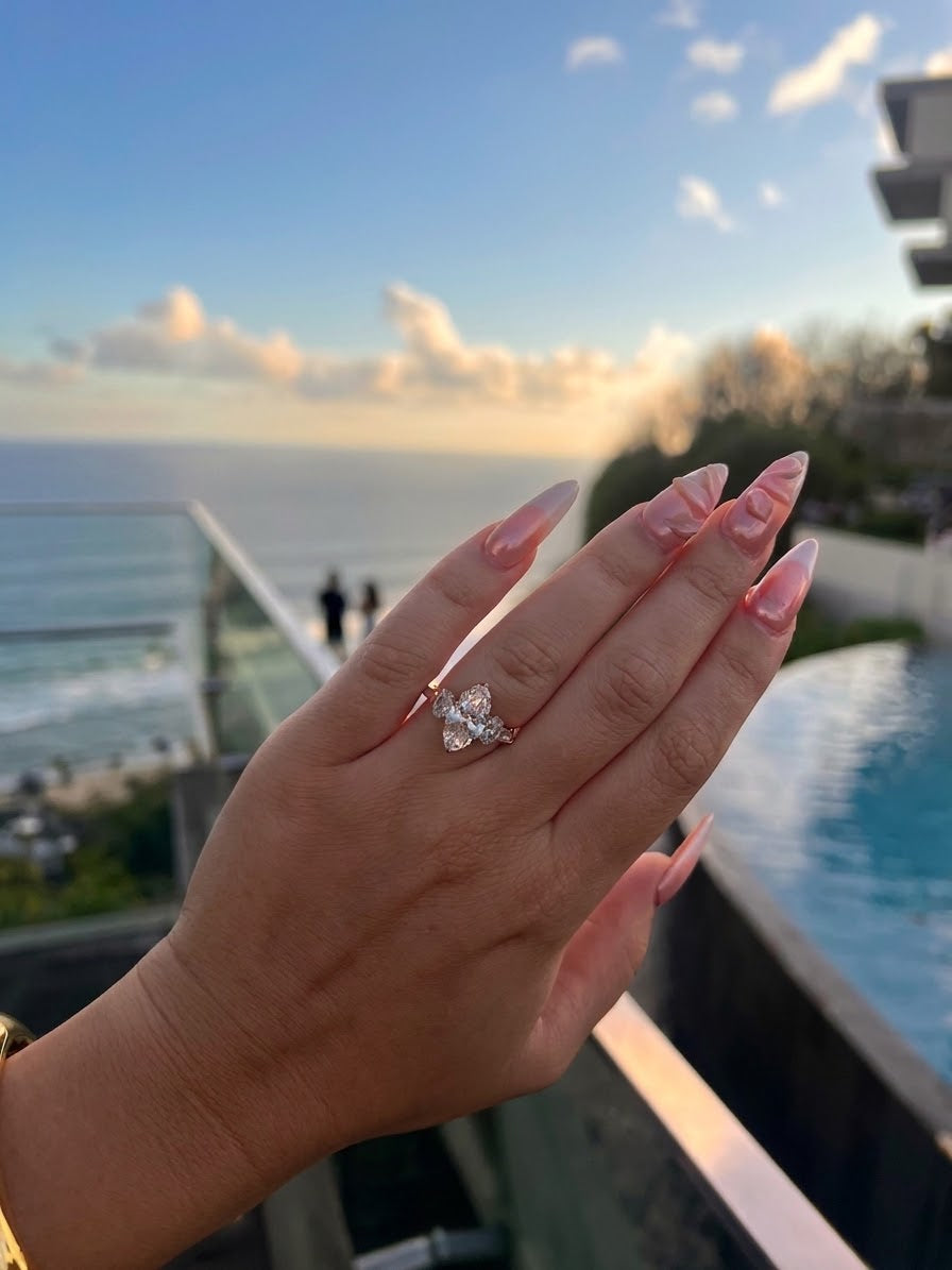 Marquise-Diamantring an einer Hand vor einem Pool mit Meerblick