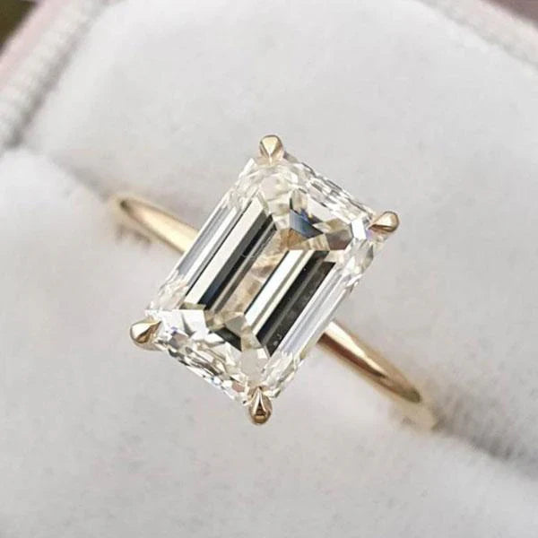 Emerald-Solitär-Verlobungsring aus Gelbgold auf hellem Stoff