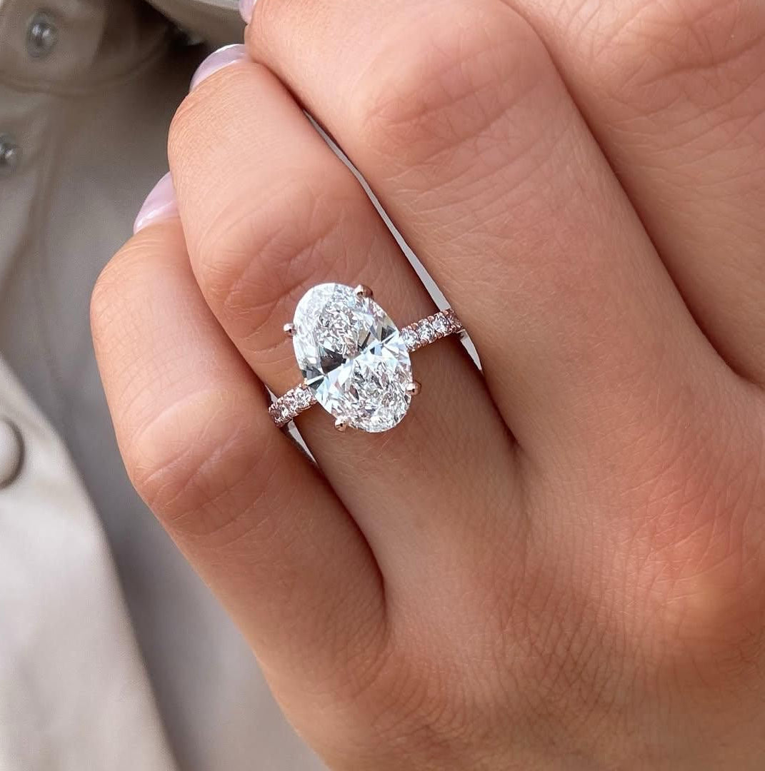 Ovaler Verlobungsring mit Diamant und Pavé-Ringschiene an der Hand