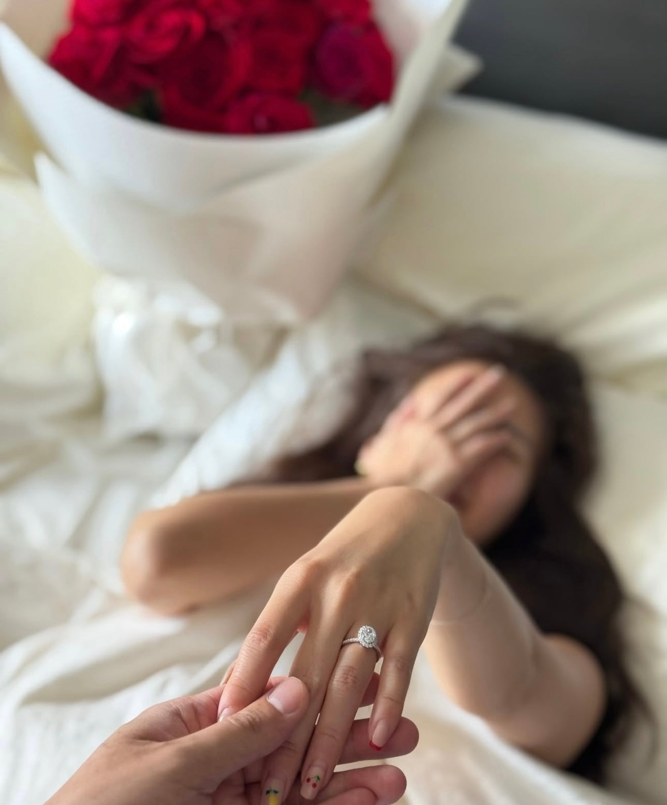 Romantischer Heiratsantrag mit Diamant-Verlobungsring am Finger der Braut, Rosenstrauß im Hintergrund – nachhaltig & zertifiziert – Labgrownlove