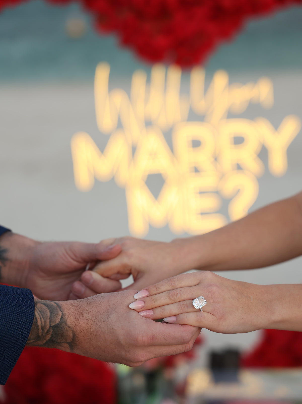 Hände mit Verlobungsring vor einem Heiratsantrag mit Marry-me-Schriftzug